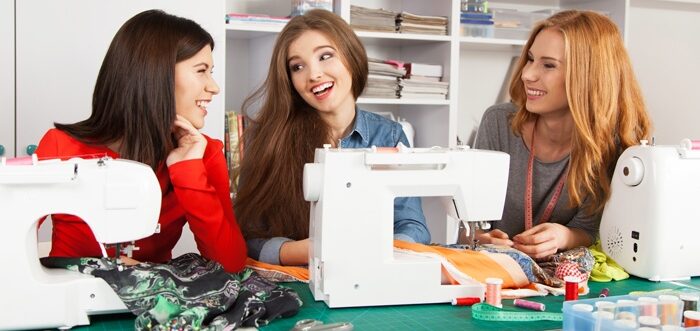 des femmes discutent ensemble autour de machines à coudres lors d'un atelier de couture.